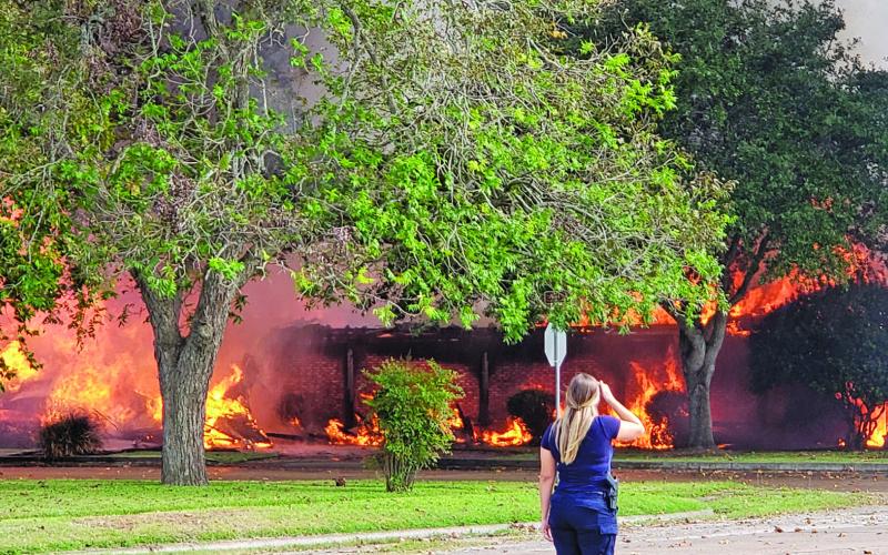 Sentinel photo/Jessica Shepard A Bay City Police Department officer looks on as Taylor Brothers Funeral Home is engulfed in flames, Friday, Oct. 22. The fire lasted three and a half hours and six local volunteer departments responded to the scene.