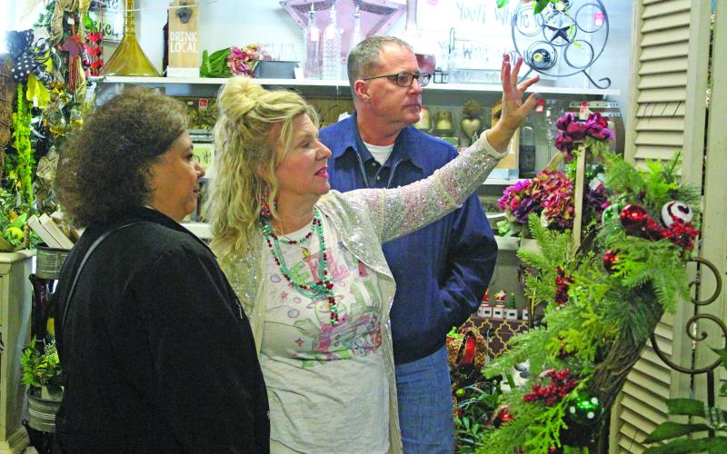 Bay City Floral owner Celeste Cash, middle, points the way to her special sale items during the annual "Christmas Around the Square" Thursday, Nov. 18. Cash was just one of several downtown business owners spreading holiday cheer, snacks, and wares that night.   Sentinel photo/ Jessica Shepard