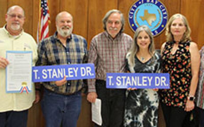 Sentinel photos/Mike Reddell At City Council’s Nov. 16 meeting, two people who have passed were recognized for their contributions to the community. Above, Bay City Regional Airport Manager James Mason (far left) is joined by family members of the late Tom Stanley, a longtime friend of the airport. Showing off T. Stanley Dr. signs for the airport are, from left: Jeffery Stanley (son), Tom Gallagher (husband of Ruth Ann Gallagher), Ruth Ann Gallagher (daughter), Debbie DuBois (stepdaughter), and LaWanda Miku