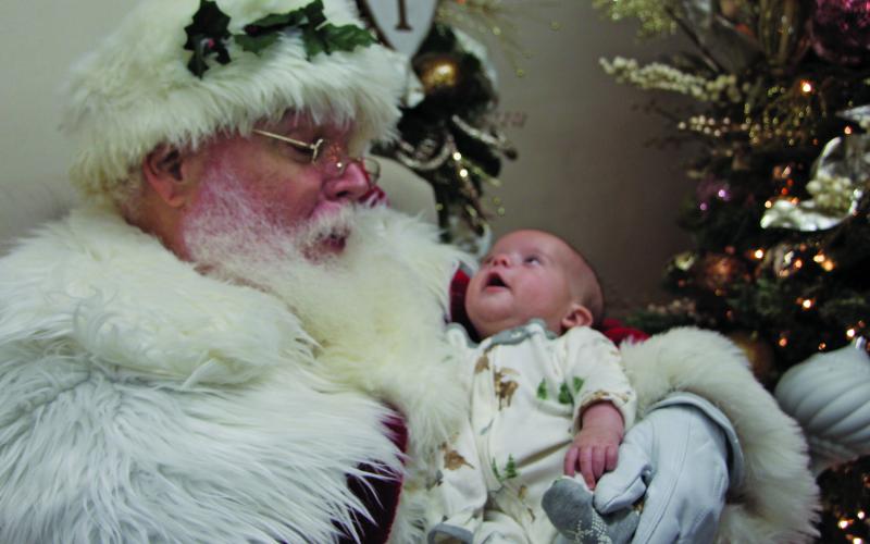 Sentinel photo/Mike Reddell Infant RJ Lane casts a wondrous look at Santa at Nia’s Towne Square Restaurant downtown Friday, Dec. 17.