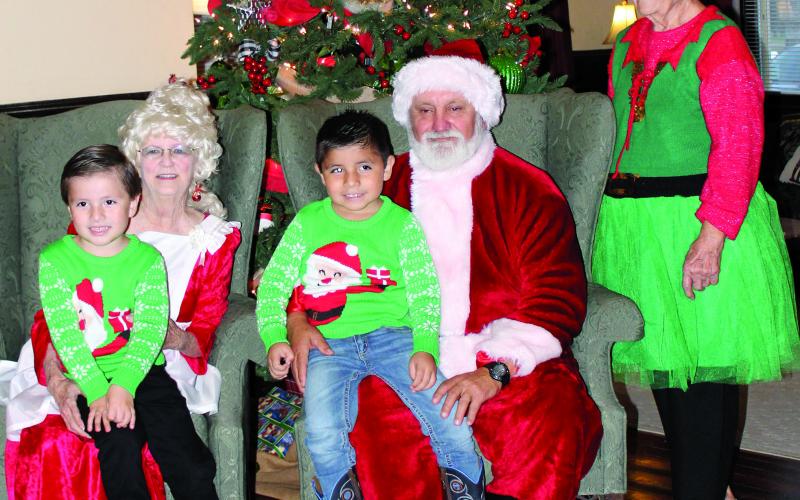 Sentinel photo/MaLinda Reddell Mr. and Mrs. Santa Claus and helper visited with two boys, Saul and Matea Garcia, at the Blessing Hotel’s annual Santa stopover Dec. 8.