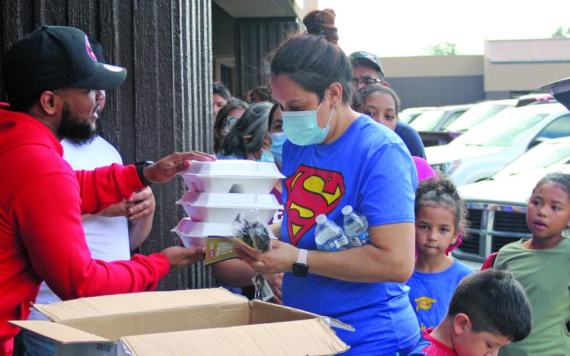 Sentinel photo/Jessica Shepard Desmond "Huncho" Sandles, left, hands out turkey dinner plates at Big Homie's Wings, Rings &amp; Stuffed Baked Potatoes restaurant Saturday, Nov. 20. The event also featured free turkey vouchers sponsored by HEB and distributed by "Growing Into Men Of Standard" for families with youth males ages 5-18 in their households.