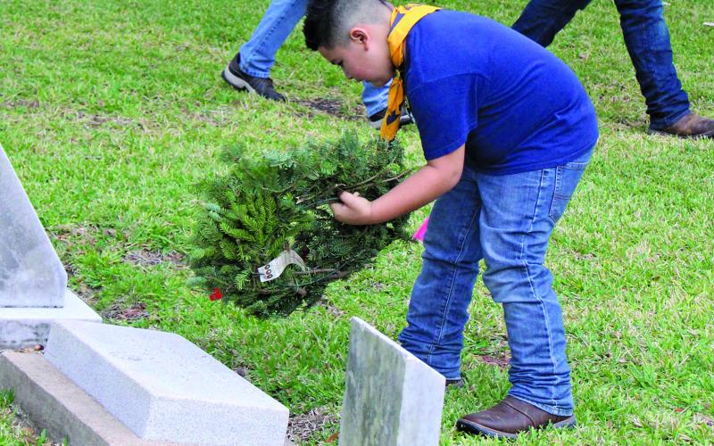 Sentinel photo/Jessica Shepard One young man placed a wreath on a grave marker at Cedarvale Cemetery Saturday, Dec. 18, as part of Wreaths Across America. Several Matagorda County cemeteries took part in the program.