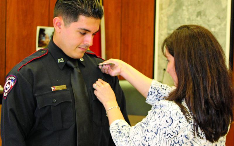 Sentinel photo/Jessica Shepard New Bay City Police Officer Tristan Trevino watches as his badge is pinned on during a swearing in ceremony Monday, 28, at City Hall Council Chambers.
