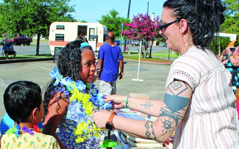 Sentinel photo/Mike Reddell Bay City Public Library's Amanda Garcia, right, hands out an assortment of colored leis as part of the library's "Community Luau" featuring Hiti Mahana Polynesia Thursday, June 23. The luau featured live music, dancing, cake, luau-themed prizes, and free books for children.