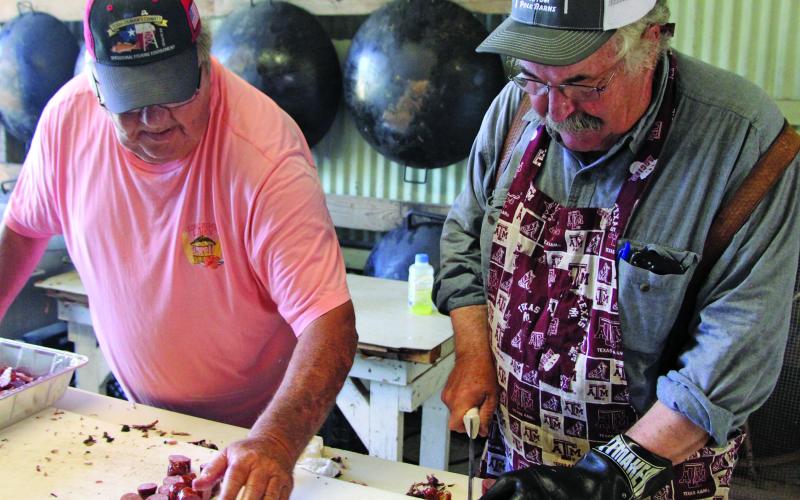 Sentinel photo/Mike Reddell Tom Klaiber, left, helps George Deshotels chop up sausage for the annual Matagorda Volunteer Fire Department barbecue fundraiser Saturday, May 28.