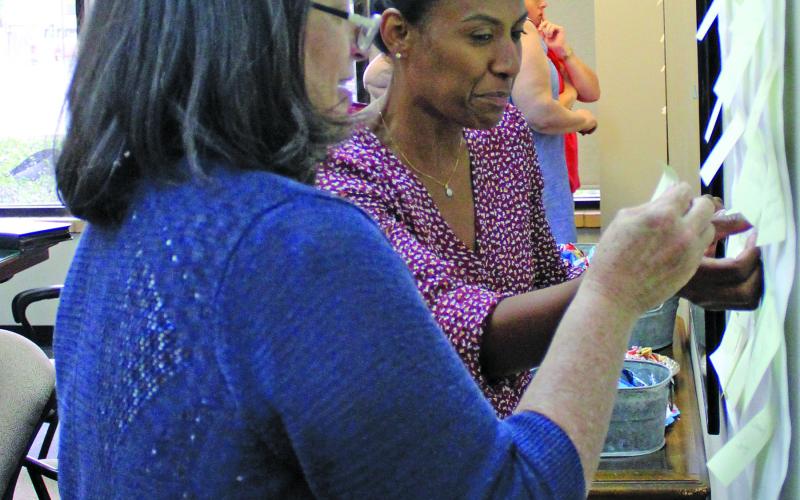 Sentinel photo/Jessica Shepard BCCDC board members Jill Cornelius and Erandi Allison organize "weakness" statements about Bay City's business atmosphere during BCCDC's goal-setting workshop Monday, June 27.