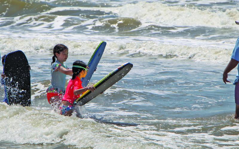 Sentinel photo/Mike Reddell A father awaits his flock of boogie boarders to teach them what waves to catch at Matagorda Beach during the Fourth of July weekend.