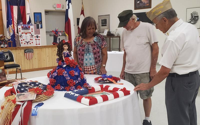 Sentinel photo/MaLinda Reddell VFW Post 1428 member Ken Thames, right, gives Jeanne and Roland Fondon of Bay City a history Sunday, Aug. 14, of the Buddy Poppy and the exhibit that’s was on display at the post.