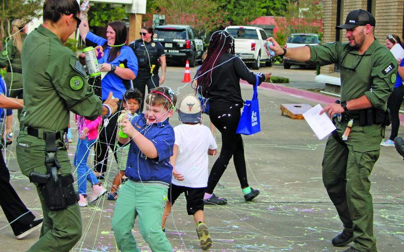 Sentinel photo/Mike Reddell Bay City police officers and others join with kids in the fun spraying Silly String during National Night Out at the Bay City Library Oct. 4.