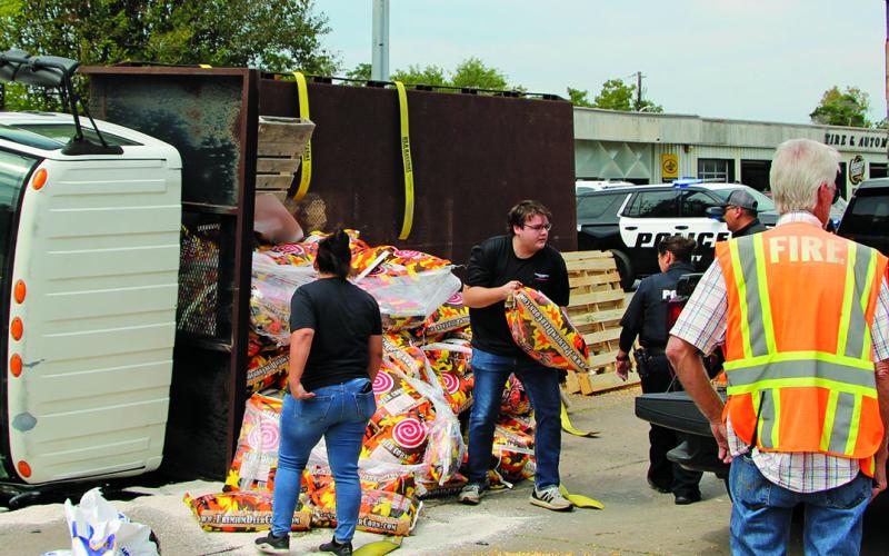 Sentinel Photo/Mike Reddell Bay City police and firefighters help move deer corn sacks from an overturned truck to another truck last week.