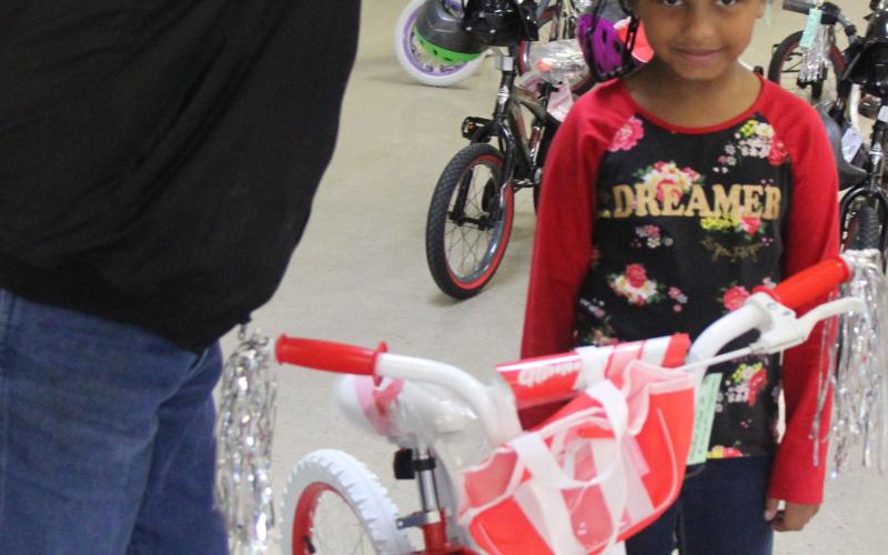 Sentinel Photo/Mike Reddell Sheriff Skipper Osborne places a helmet on a girl who got one of the bikes.