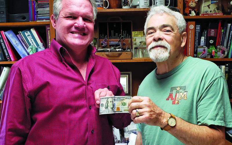 Sentinel Photo/Jessica Shepard Bay City physician Dr. Dane Simons, left, receives a $100 bill from Bay City Sentinel Editor Mike Reddell for being the top prognosticator in the Sentinel’s annual football panel.