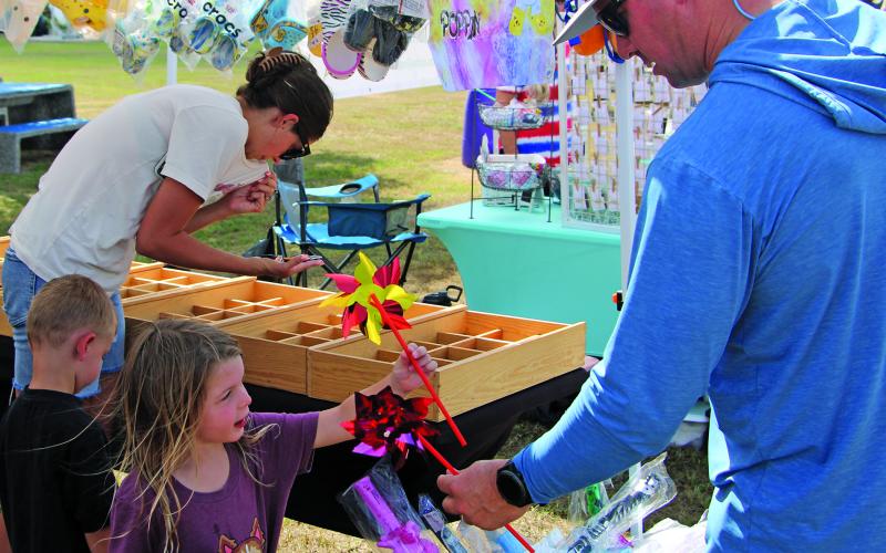 Sentinel Photo/Mike Reddell A father presents a whirligig to his daughter at the Matagorda Historical Society Christmas in July fundraiser at Heritage Park in Matagorda Saturday, July 1.