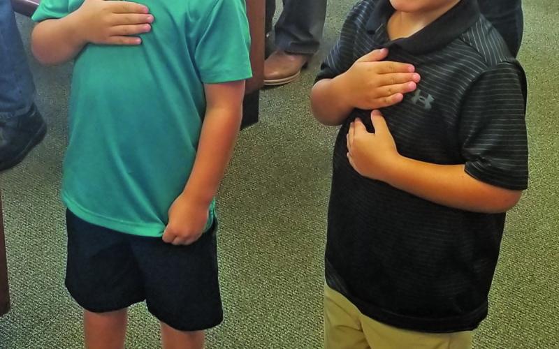Commissioner Mike Estlinbaum’s grandsons, Connor (left) and Luke, lead the court’s pledges. Sentinel Photo/Mike Reddell