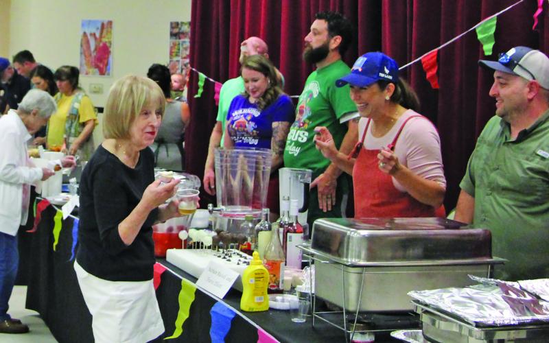 Sentinel file photo Connie Cornman visits with cooking team at last year’s Gourmet Guys.