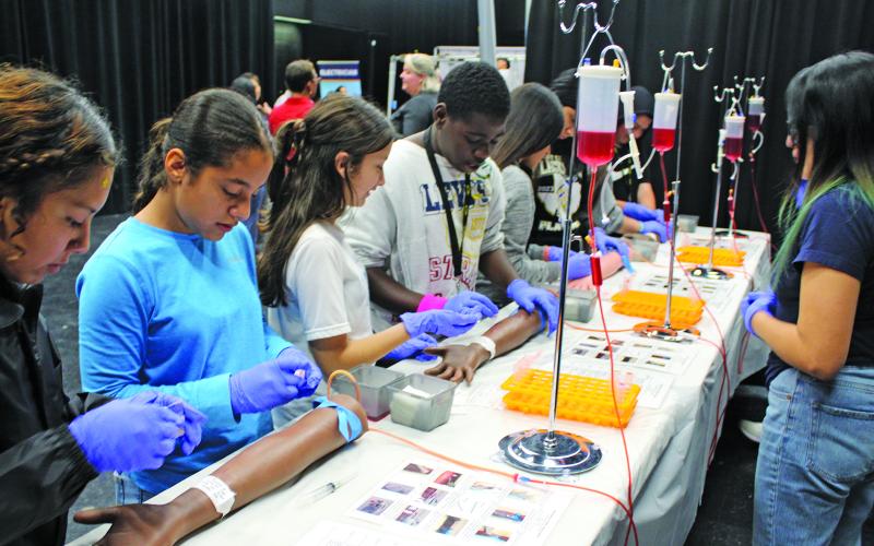 Sentinel Photo/Jessica Shepard Bay City Junior High students get a chance to experience a mock career demonstration on how a phlebotomist performs their job then try their hand at drawing “blood” at BridgeYear’s “Career Test Drive Fair” on Oct. 12. The BridgeYear event was made possible by a $15,000 TDECU donation.