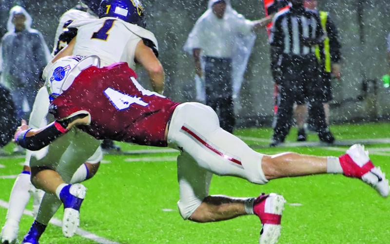 LeDarion Stone/Live in the Moment Photography Tidehaven defensive End Justin Griffith (44) makes a diving tackle on a Buffalo running back in the driving rain.