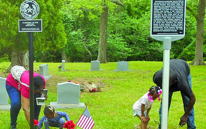 Contributed photo Two little kids get some help from adults in placing flowers at the base of markers for Allenhurst Community, and Allenhurst Cemetery Historic Texas Cemetery.