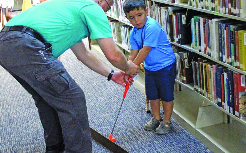 Sentinel Photo/Jessica Shepard The Bay City Public Library kicked off its summer reading program with "Library Mini Golf" Monday. Children and adults of all ages took shots through winding fairways and obstacles ranging from stuffed snakes and zebras to angled tracks and ramps.