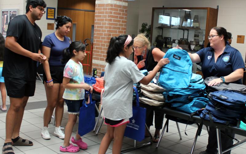 Sentinel Photo/Jessica Shepard Volunteers passed out backpacks from bulging stacks of different styles and colors at the BCISD Back to School Bash last week.