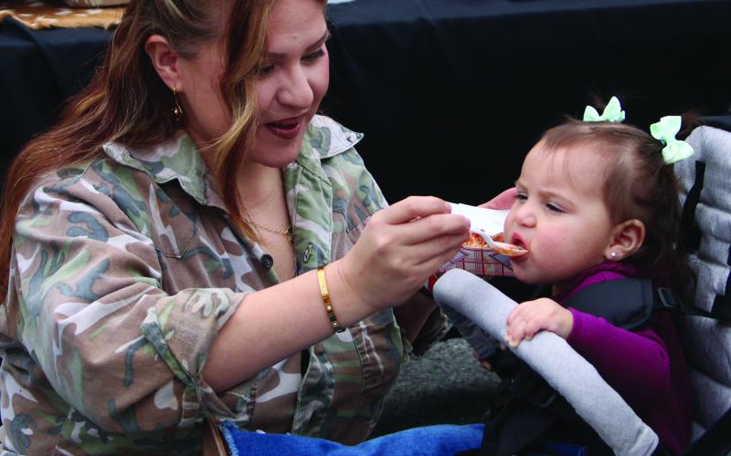 A mother offers her child a small taste of Camofest cuisine downtown Bay City Satur- day, Jan. 25. The annual event drew at least a dozen food vendors featuring a vast array of different tastes. Sentinel Photo/Mike Reddell