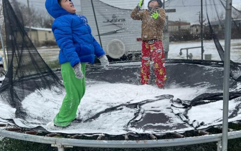 Jonathan Nendo (blue jacket) and Jayson Nendo share fun time on a snow covered trampoline.