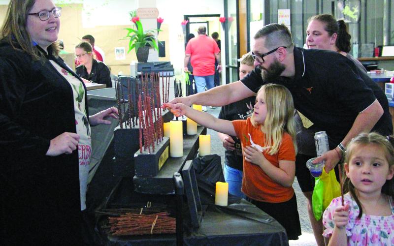 Sentinel Photo/Jessica Shepard Communications and Cultural Arts Director Samantha Denbow helps parents and kids pick out their favorite Harry Potter wands as Bay City Public Library hosted its 4th Annual Harry Potter Book Day Thursday, March 13.