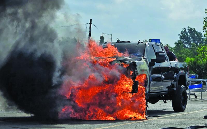 Sentinel Photo/MaLinda Reddell A Bay City firefighter stands by as Fire Marshal Dan Shook retrieves items from a burning truck in Walmart’s parking lot soon after the driver left the vehicle.