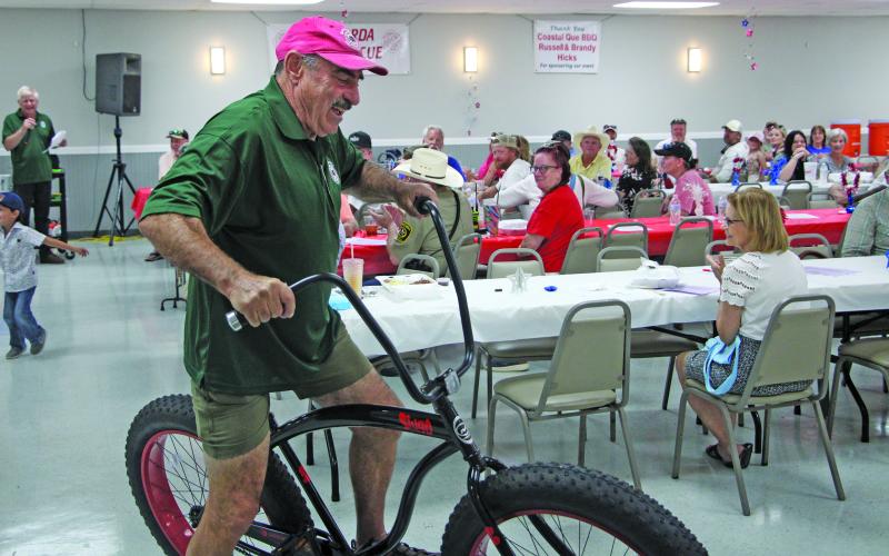 Sentinel Photo/Mike Reddell A firefighter shows off a bike up for auction at the Matagorda VFD BBQ Saturday, May 24.