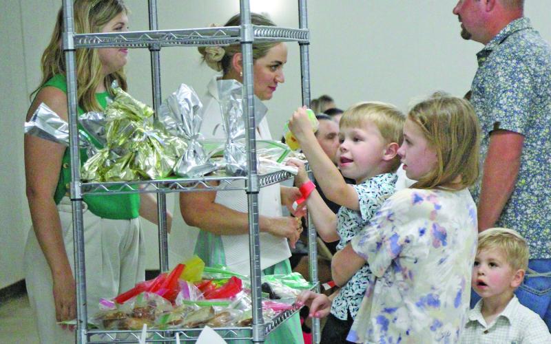 Children, at left, used teamwork to help each other pick out their chosen desserts at Holy Cross Catholic School's annual "Bazaar" Sunday, April 27. The event also featured carnival-style games, raffles and a live auction. Sentinel Photo/ Jessica Shepard