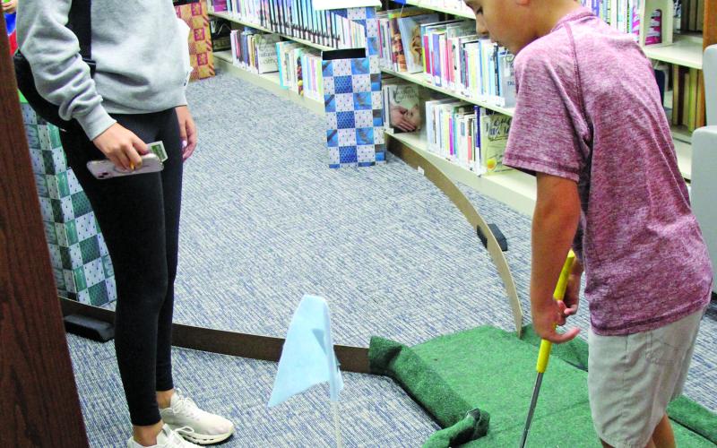 Sentinel Photos/Jessica Shepard Friends of the Bay City Public Library brought back their "Library Mini Golf" fundraiser on Tuesday, July 22. Children and adults of all ages took shots through winding fairways and obstacles ranging from stuffed animals to angled tracks and ramps and a vibrant fairway finish line.