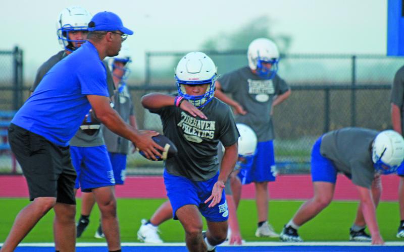 Photo by Anna Hernandez A Tidehaven coach hands off to a Tiger running back during workouts last week. Tidehaven will scrimmpage Shiner at home Friday.