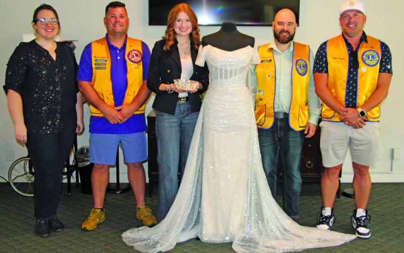Sentinel Photo/Jessica Shepard Bay City Lions Club members pose with this year’s Rice Festival Queen dress, sponsored by New Beginnings Bridal &amp; Prom in El Campo on Sept. 5. Pictured from left are: Lions Club Rice Festival Queen Pageant Director Rachel Ricks, Lions Club President Mike Griffith, New Beginnings Bridal &amp; Prom representative Kasey Burns, Lions Club Rice Festival Queen Pageant Chairman Ryan Ricks, and Lions Club Rice Festival Chairman Trent Tinnin.