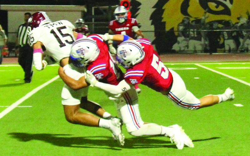 Anna Hernandez photo Left, the Halletsville ball carrier didn’t get very far carrying the ball with two Tidehaven defenders on his back -  Bryce Sliva (6) and Levi Piwonka (5).