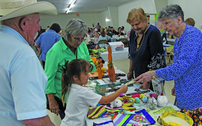 Sentinel Photo/Jessica Shepard A little girl accepts a payment for an item under the watchful eye of her grandfather at the Holy Cross Catholic Church’s annual “Fall Festival and Turkey Dinner” Sunday, Sept. 29, at the Knights of Columbus Hall. The church’s event featured a live auction, raffle, country store, and children’s activities.