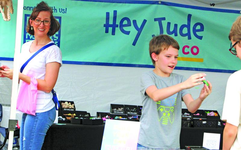 Sentinel Photo/Jessica Shepard Customers braved ominous skies to shop at Downtown Bay City Market Day on Saturday, Nov. 22. Vendors showed off a variety of potential Christmas gifts, like one youngster, center, showing off a 3D-printed fidget toy.
