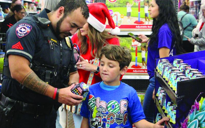Sentinel Photo/Jessica Shepard A Bay City police officer helps a boy read instructions on a gift during Shop with a Cop at Walmart Dec. 11. More than 40 children benefited from the annual event where Bay City Police Department joins with law enforcement agencies and non-profits from across Matagorda County.