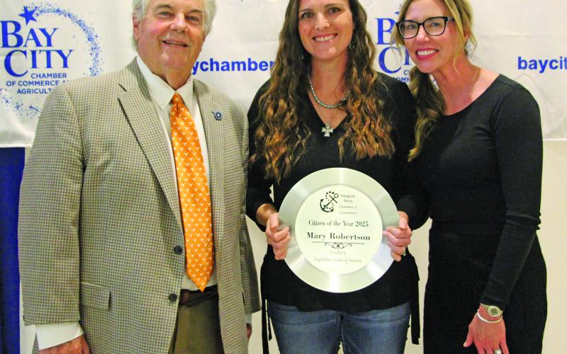 Sentinel Photo/Jessica Shepard Mary Robertson shows off her Sargent Area Chamber of Commerce Citizen of the Year 2025 honor at the Bay City Chamber of Commerce &amp; Agriculture at its banquet Jan. 15. Shown with Robertson are outgoing board chair John Dickerson and Chair-elect Savannah Cornelius.