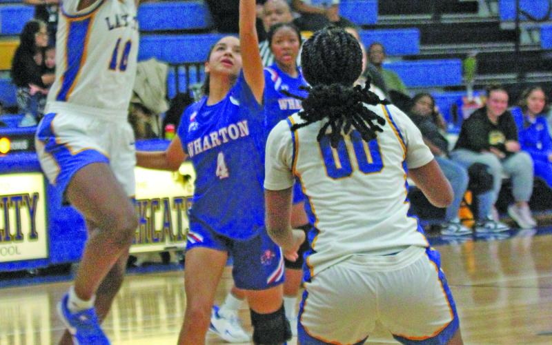 Photo by Anna Hernandez Bay City girls played Wharton here Friday, Feb. 6. Above, Lady Cat junior center Sasha Orwucheknia goes up high to battle Wharton players. Senior Kam Davis (00) positions herself to help.