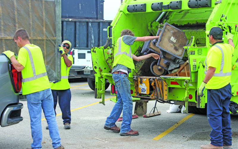 Sentinel Photo/Jessica Shepard GFL Environmental employees work together to unload a truck bed as part of the City of Bay City's "Annual Spring Clean-up" on Saturday, April 25.