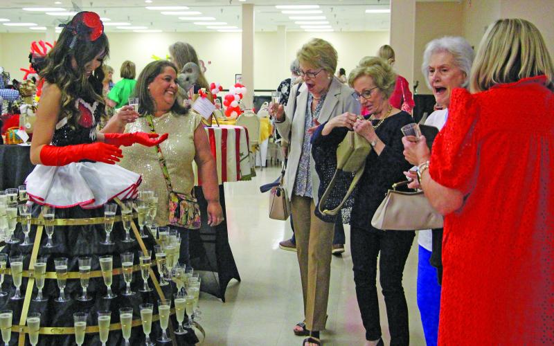 Sentinel Photo/Jessica Shepard Matagorda County Medical Center Foundation "Power of the Purse: Under the Big Top" attendees were greeted by a woman wearing tiers of drinks, left, upon entering the event on Thursday, April 23. Other attractions included a fortune teller and over 100 unique purses and bidding packages to purchase..