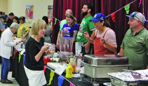 Sentinel file photo Connie Cornman visits with cooking team at last year’s Gourmet Guys.