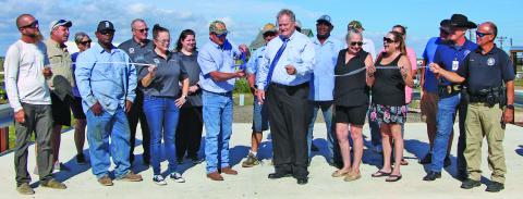 Sentinel Photo/Mike Reddell Precinct 2 hosted a grand opening for the new bridge on County Road 201 in Sargent last week. In the center, Precinct 2 Commissioner Mike Estlinbaum (with cap) and County Judge Bobby Seiferman cut the ribbon.