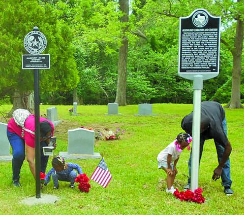 Contributed photo Two little kids get some help from adults in placing flowers at the base of markers for Allenhurst Community, and Allenhurst Cemetery Historic Texas Cemetery.