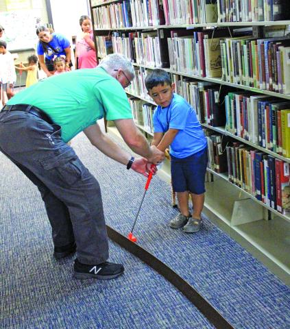 Sentinel Photo/Jessica Shepard The Bay City Public Library kicked off its summer reading program with "Library Mini Golf" Monday. Children and adults of all ages took shots through winding fairways and obstacles ranging from stuffed snakes and zebras to angled tracks and ramps.