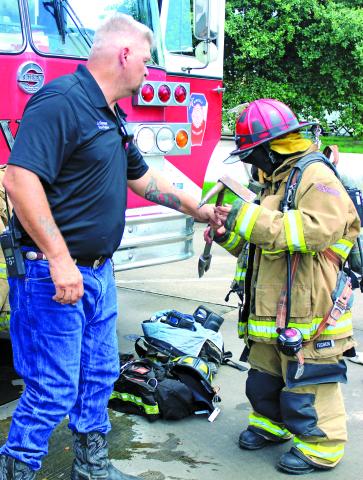 Sentinel photo/Jessica Shepard Bay City Public Library hosted "Hometown Heroes" featuring the Bay City Police Department, Bay City Municipal Court, the Crisis Center, Tenaris, and Midfield Fire Department Monday, July 29. Above, Juliana Maldonado tries on Midfield Volunteer Fire Department bunker gear during the Bay City Public Library's "Hometown Heroes" event.