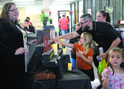 Sentinel Photo/Jessica Shepard Communications and Cultural Arts Director Samantha Denbow helps parents and kids pick out their favorite Harry Potter wands as Bay City Public Library hosted its 4th Annual Harry Potter Book Day Thursday, March 13. 