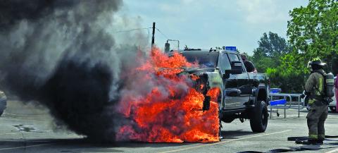 Sentinel Photo/MaLinda Reddell A Bay City firefighter stands by as Fire Marshal Dan Shook retrieves items from a burning truck in Walmart’s parking lot soon after the driver left the vehicle.