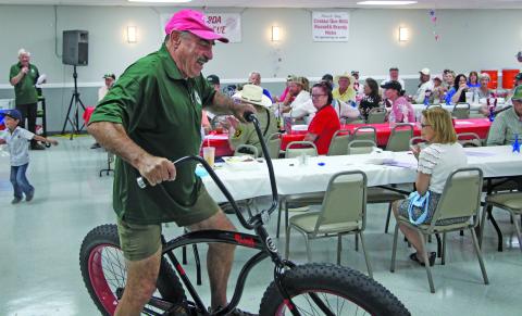 Sentinel Photo/Mike Reddell A firefighter shows off a bike up for auction at the Matagorda VFD BBQ Saturday, May 24.